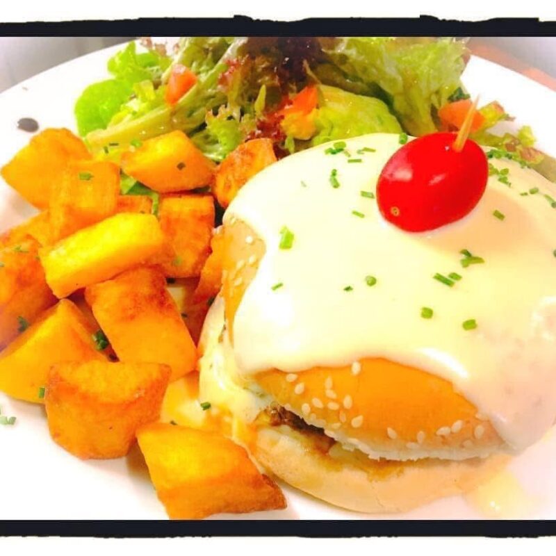 Burger gourmand au fromage fondu avec pommes de terre sautées et salade