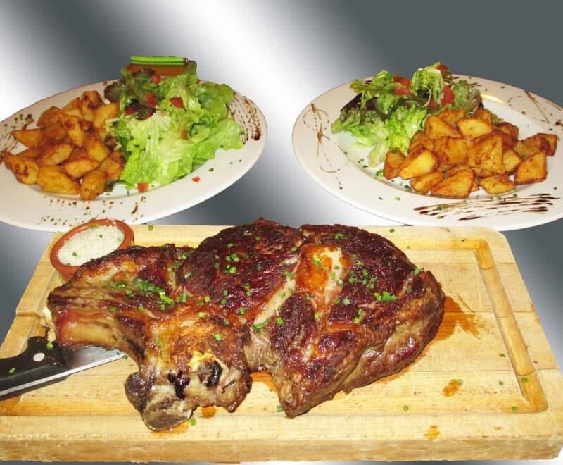 Côte de boeuf grillée servie avec salade mesclun et pommes de terre sautées